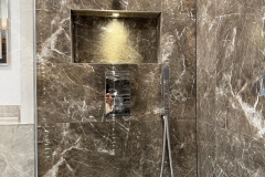 Monochrome walk in shower with back lit shelf and shower